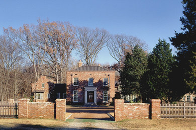 Large traditional red two-story brick exterior home idea in Other