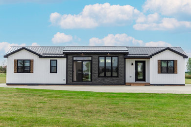 Small minimalist white one-story vinyl and board and batten tiny house photo in Toronto with a black roof