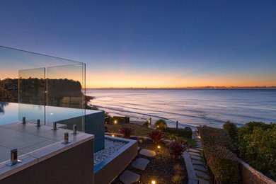Design ideas for a large contemporary backyard rectangular infinity pool in Sydney with with a pool and natural stone pavers.