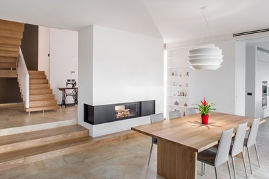 Idee per una sala da pranzo aperta verso il soggiorno contemporanea con pareti bianche, camino bifacciale e pavimento beige