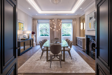 Photo of a large traditional enclosed dining room in London with beige walls, medium hardwood flooring, a standard fireplace, a stone fireplace surround, brown floors, a coffered ceiling and panelled walls.