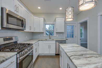 Inspiration for a mid-sized transitional l-shaped dark wood floor and brown floor enclosed kitchen remodel in Boston with an undermount sink, shaker cabinets, white cabinets, marble countertops, gray backsplash, subway tile backsplash, stainless steel appliances, an island and white countertops