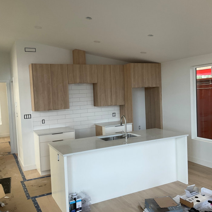 New kitchen under construction with vertical grain wood cabinets and tile backsplash