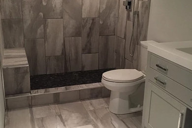 Example of a mid-sized trendy master beige tile, gray tile and porcelain tile porcelain tile and gray floor bathroom design in Calgary with recessed-panel cabinets, gray cabinets, a two-piece toilet, gray walls, an integrated sink, quartz countertops and white countertops