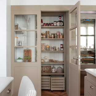 Klassische Küche mit integriertem Waschbecken, beigen Schränken, Quarzwerkstein-Arbeitsplatte, Küchenrückwand in Weiß, Rückwand aus Keramikfliesen, Küchengeräten aus Edelstahl, hellem Holzboden, Kücheninsel, braunem Boden und Vorratsschrank in Barcelona