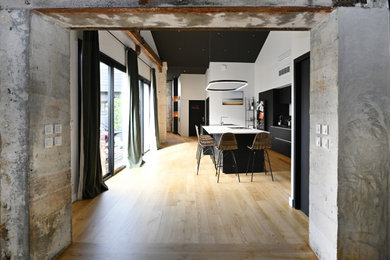 Réalisation d'une grande cuisine ouverte linéaire, encastrable, bicolore et noire et bois minimaliste avec un évier encastré, un placard à porte plane, des portes de placard noires, un plan de travail en surface solide, une crédence blanche, une crédence en marbre, parquet clair, îlot et un plan de travail blanc.