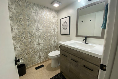 Example of a small transitional ceramic tile, beige floor, single-sink and wallpaper bathroom design in Salt Lake City with gray cabinets, a two-piece toilet, white walls, an integrated sink, white countertops and a freestanding vanity