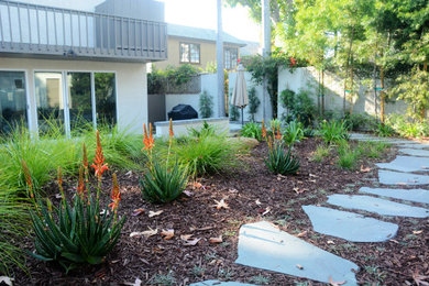 Large backyard partial sun driveway in Los Angeles with a garden path and natural stone pavers.