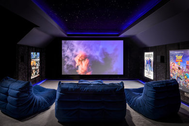 This is an example of a small modern enclosed home cinema in Surrey with black walls, carpet, a projector screen, grey floors and feature lighting.