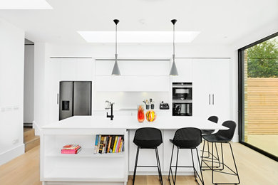 На фото: прямая кухня среднего размера в современном стиле с обеденным столом, плоскими фасадами, белыми фасадами, островом и белой столешницей с