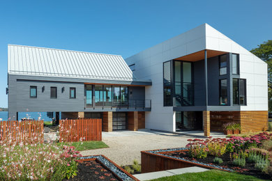 Foto de fachada de casa gris actual de tres plantas con revestimientos combinados, tejado a dos aguas y tejado de metal