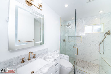 Corner shower - mid-sized modern 3/4 white tile and porcelain tile porcelain tile, white floor and single-sink corner shower idea in Los Angeles with raised-panel cabinets, white cabinets, a one-piece toilet, white walls, solid surface countertops, a hinged shower door, white countertops and a freestanding vanity