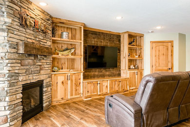 Mid-sized mountain style walk-out laminate floor and brown floor basement photo in Minneapolis with a bar, green walls, a corner fireplace and a stone fireplace