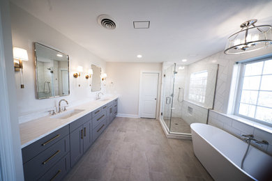 Mid-sized trendy master white tile and subway tile ceramic tile, beige floor and double-sink bathroom photo in New York with shaker cabinets, blue cabinets, a one-piece toilet, white walls, a drop-in sink, granite countertops, a hinged shower door, white countertops, a niche and a built-in vanity