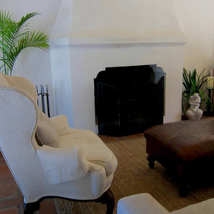 Kleines, Abgetrenntes Mediterranes Wohnzimmer mit weißer Wandfarbe, Terrakottaboden, Kamin, Kaminsims aus Beton und rotem Boden in Santa Barbara