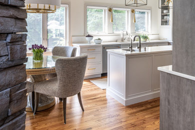 Example of a mid-sized transitional l-shaped dark wood floor and brown floor eat-in kitchen design in Philadelphia with an undermount sink, flat-panel cabinets, beige cabinets, quartz countertops, beige backsplash, ceramic backsplash, stainless steel appliances, an island and white countertops
