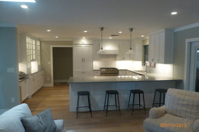 Large trendy u-shaped light wood floor eat-in kitchen photo in Phoenix with a drop-in sink, shaker cabinets, white cabinets, solid surface countertops, white backsplash, ceramic backsplash, stainless steel appliances and a peninsula