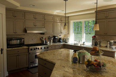 Example of a large arts and crafts u-shaped eat-in kitchen design in Seattle with shaker cabinets, distressed cabinets, a peninsula, granite countertops, beige backsplash and stone tile backsplash