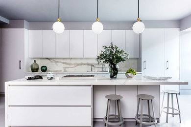 Contemporary kitchen in London with marble worktops and an island.