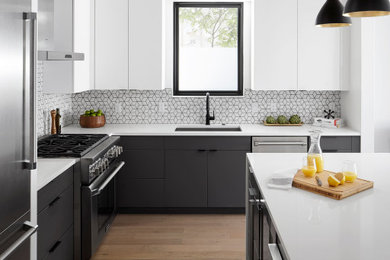 Design ideas for a mid-sized contemporary l-shaped kitchen in Austin with flat-panel cabinets, grey cabinets, quartzite benchtops, white splashback, porcelain splashback, stainless steel appliances, medium hardwood floors, with island, white benchtop, an undermount sink and brown floor.