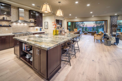 This is an example of a mid-sized transitional l-shaped open plan kitchen in Sacramento with an undermount sink, shaker cabinets, dark wood cabinets, granite benchtops, beige splashback, mosaic tile splashback, stainless steel appliances, light hardwood floors, with island and multi-coloured benchtop.