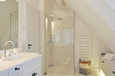 Mittelgroßes Maritimes Duschbad mit Schrankfronten im Shaker-Stil, weißen Schränken, bodengleicher Dusche, weißer Wandfarbe, integriertem Waschbecken, beigem Boden und Falttür-Duschabtrennung in Sonstige