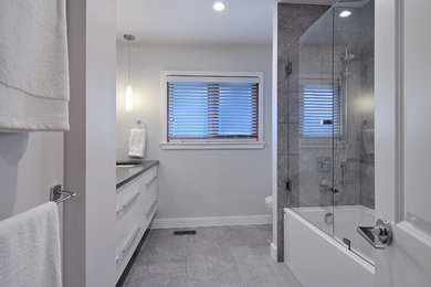 This is an example of a contemporary bathroom in Vancouver with flat-panel cabinets, white cabinets, an alcove tub, a shower/bathtub combo, grey walls, porcelain floors, an undermount sink, grey floor and a hinged shower door.
