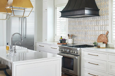 Example of a mid-sized beach style l-shaped medium tone wood floor and brown floor open concept kitchen design in Grand Rapids with a farmhouse sink, shaker cabinets, white cabinets, quartz countertops, multicolored backsplash, terra-cotta backsplash, stainless steel appliances, an island and white countertops