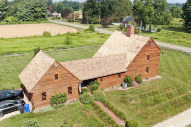 Foto de fachada de casa marrón y roja campestre grande de tres plantas con revestimiento de madera, tejado a dos aguas, tejado de teja de madera y tablilla