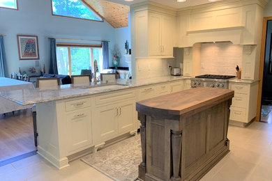 Open concept kitchen - mid-sized traditional u-shaped porcelain tile and beige floor open concept kitchen idea in Milwaukee with a double-bowl sink, recessed-panel cabinets, white cabinets, quartz countertops, white backsplash, ceramic backsplash, stainless steel appliances, an island and multicolored countertops