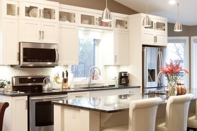 Example of a large arts and crafts single-wall dark wood floor eat-in kitchen design in Calgary with a double-bowl sink, shaker cabinets, white cabinets, solid surface countertops, white backsplash, subway tile backsplash, stainless steel appliances and an island