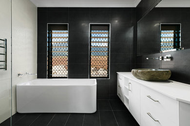 Inspiration for a mid-sized kids bathroom in Cairns with white cabinets, a freestanding tub, a double shower, black and white tile, ceramic tile and limestone benchtops.