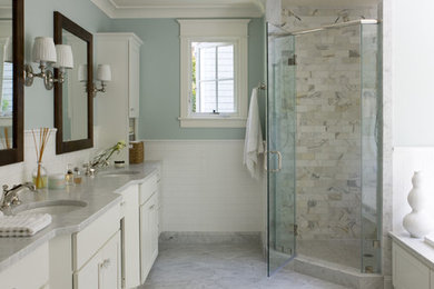 This is an example of a traditional bathroom in DC Metro with an undermount sink, recessed-panel cabinets, white cabinets, a corner shower, white tile, blue walls, grey floor and grey benchtops.