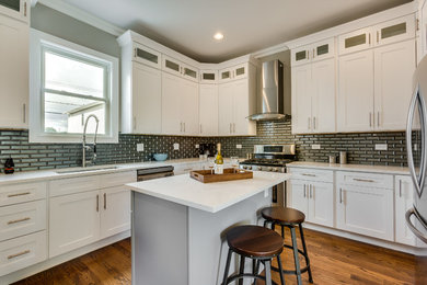Inspiration for a transitional l-shaped dark wood floor kitchen remodel in Chicago with an undermount sink, shaker cabinets, white cabinets, black backsplash, subway tile backsplash, stainless steel appliances and an island
