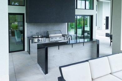 Inspiration pour une terrasse arrière minimaliste de taille moyenne avec une cuisine d'été, du carrelage et une extension de toiture.