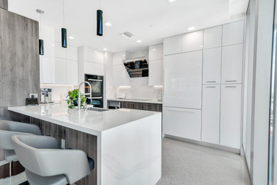 Inspiration for a mid-sized modern u-shaped marble floor and white floor open concept kitchen remodel in Miami with a farmhouse sink, flat-panel cabinets, gray cabinets, quartz countertops, white backsplash, quartz backsplash, paneled appliances and white countertops