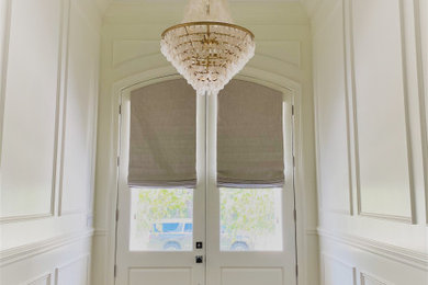 Elegant light wood floor and wainscoting double front door photo in New Orleans with white walls and a white front door