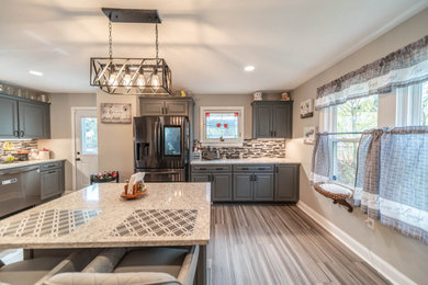 Example of a large minimalist vinyl floor and gray floor kitchen design in Cleveland with gray cabinets, granite countertops, gray backsplash, mosaic tile backsplash, stainless steel appliances and an island