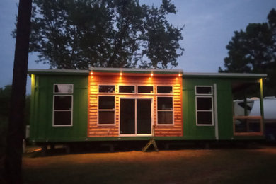 Small beach style green one-story wood and board and batten tiny house photo in Miami with a shed roof, a metal roof and a white roof