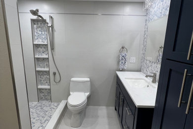 Ejemplo de cuarto de baño único y de pie pequeño con armarios estilo shaker, puertas de armario azules, sanitario de una pieza, baldosas y/o azulejos grises, baldosas y/o azulejos de porcelana, aseo y ducha, encimera de cuarcita y encimeras blancas