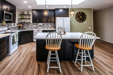 Inspiration for a mid-sized transitional l-shaped vinyl floor and brown floor kitchen pantry remodel in Cleveland with an undermount sink, flat-panel cabinets, black cabinets, quartz countertops, multicolored backsplash, mosaic tile backsplash, white appliances, an island and white countertops