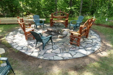 Example of a mountain style side yard stone patio design in Other with a fire pit