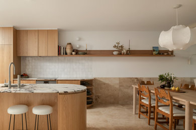 Inspiration for a mid-sized tropical single-wall travertine floor and brown floor eat-in kitchen remodel in Sunshine Coast with a single-bowl sink, light wood cabinets, marble countertops, white backsplash, ceramic backsplash, stainless steel appliances, an island and black countertops
