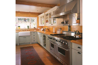 Medium sized country l-shaped kitchen pantry in San Francisco with a belfast sink, shaker cabinets, green cabinets, wood worktops, orange splashback, integrated appliances, light hardwood flooring and no island.