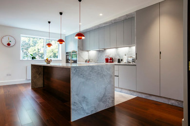 Photo of an expansive contemporary kitchen/diner in London with an integrated sink, flat-panel cabinets, marble worktops and medium hardwood flooring.