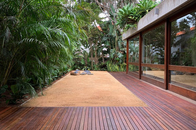 Large tropical backyard full sun formal garden in Sydney with gravel for summer.