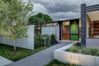 Inspiration for a large contemporary gray two-story brick house exterior remodel in Dallas with a shed roof and a metal roof