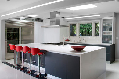 Design ideas for a large modern l-shaped eat-in kitchen in Chicago with flat-panel cabinets, white cabinets, solid surface benchtops, stainless steel appliances, with island, an undermount sink, porcelain floors and white floor.