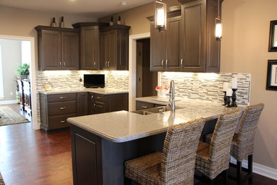 Enclosed kitchen - mid-sized transitional u-shaped dark wood floor enclosed kitchen idea in Huntington with an undermount sink, raised-panel cabinets, gray cabinets, solid surface countertops, gray backsplash, glass tile backsplash and stainless steel appliances