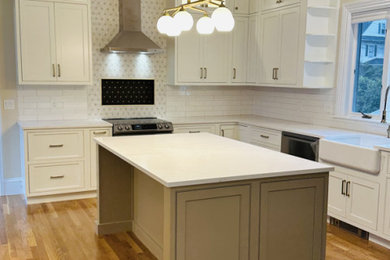 Design ideas for a large traditional l-shaped eat-in kitchen in Boston with a farmhouse sink, shaker cabinets, white cabinets, quartz benchtops, white splashback, mosaic tile splashback, stainless steel appliances, light hardwood floors, with island and white benchtop.